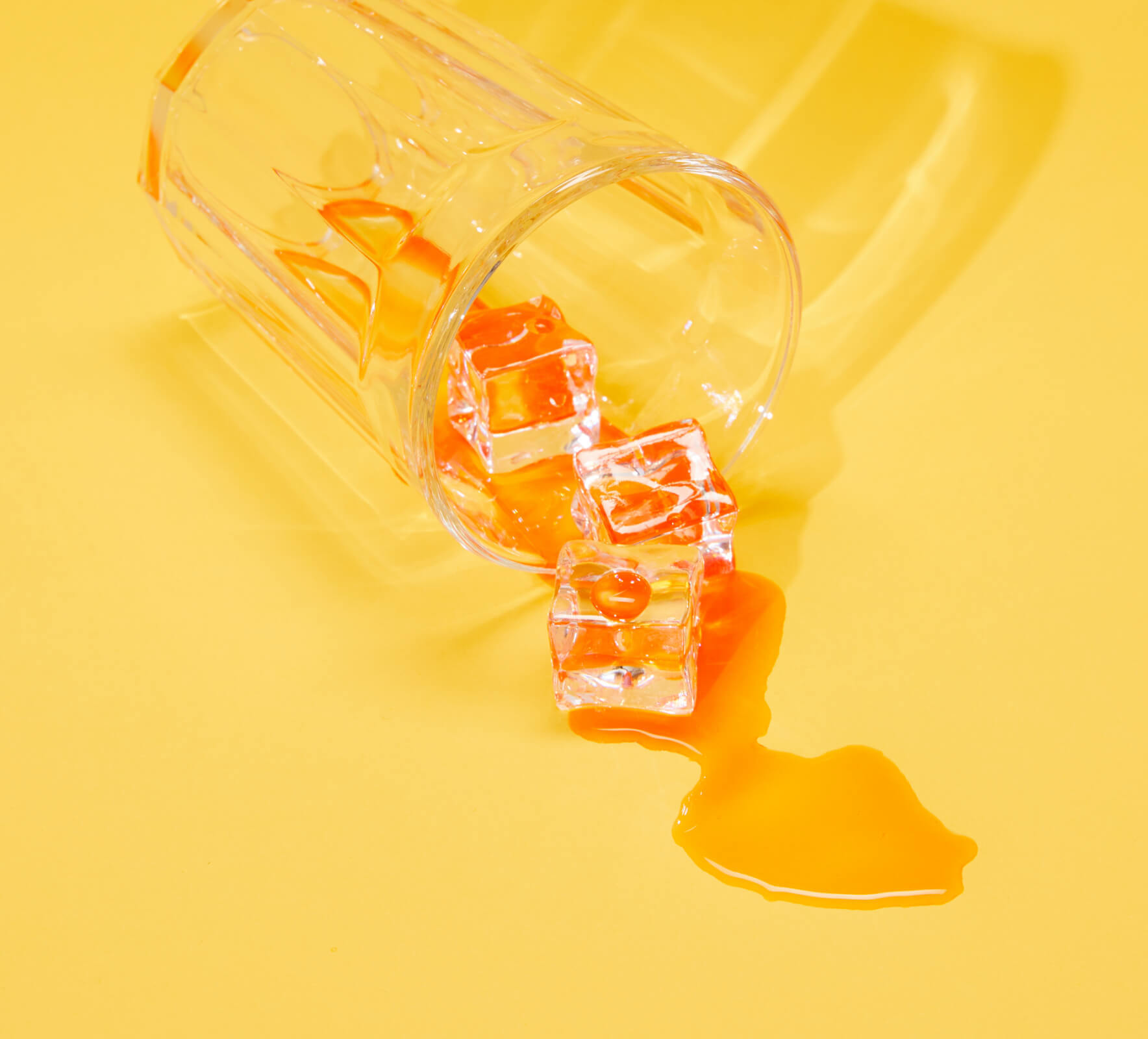 A glass of spilt tea with ice cubes